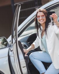 Young attractive woman just bought a new car. female holding keys from new automobile.